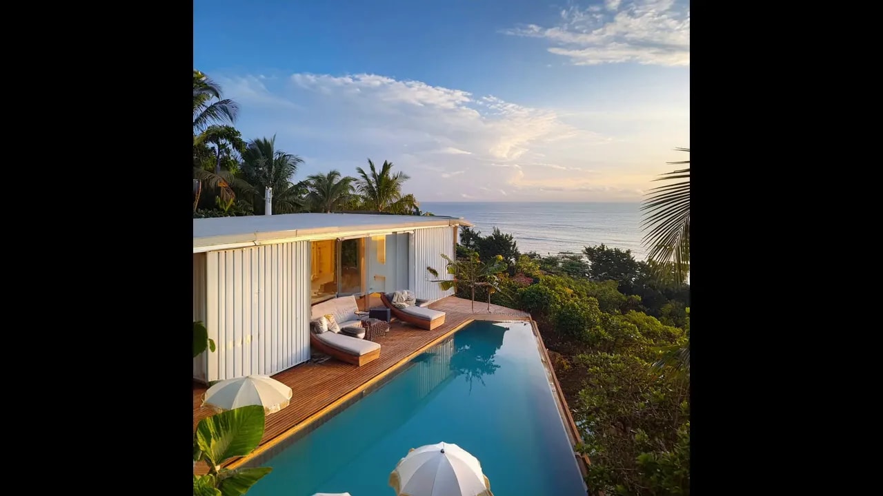 White modern home with long curved pool overlooking tropical hillside and ocean