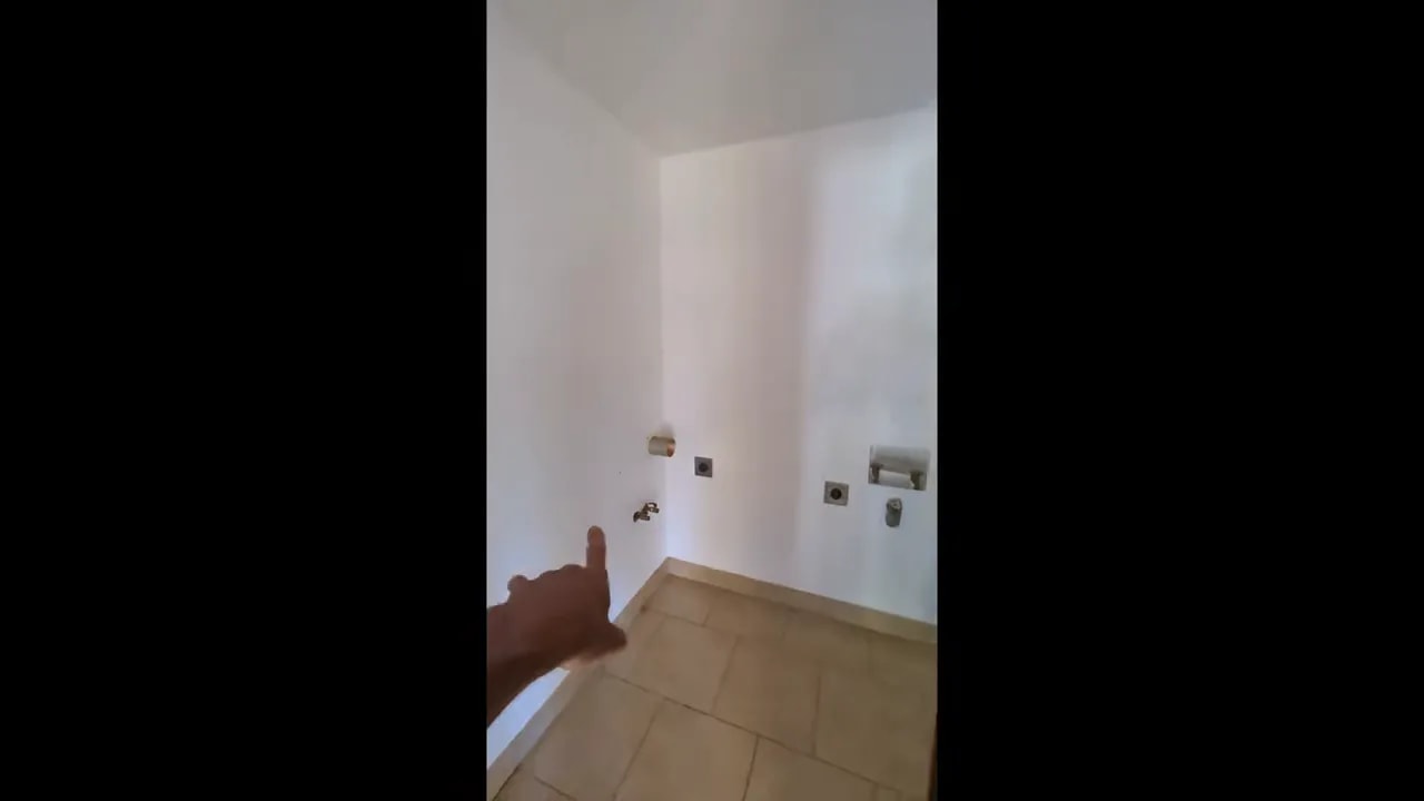 Small laundry room with utility hookups on white walls