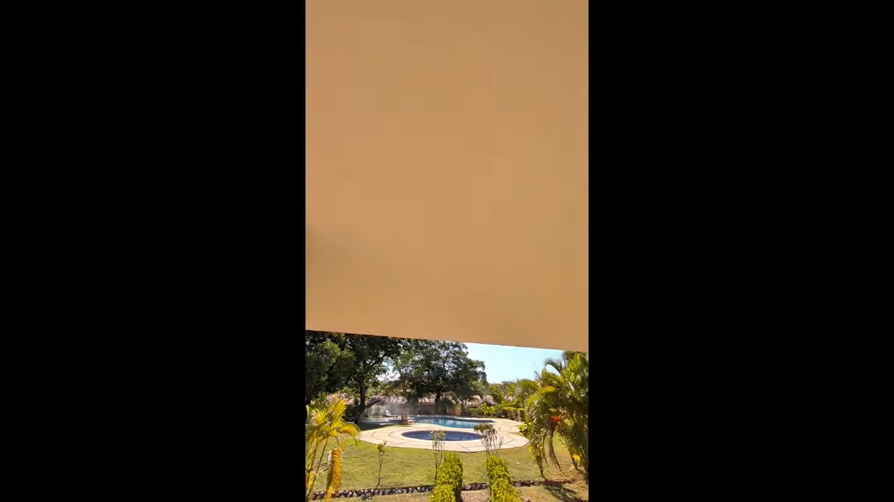Underside of covered patio roof with view toward landscaping and pool area