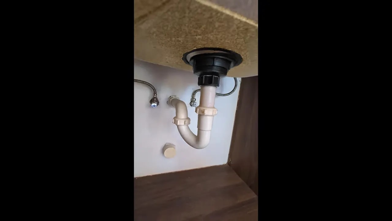 Under-sink plumbing and cabinet interior beneath the kitchen counter